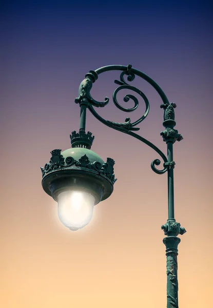 Old illuminated street lamp at night.