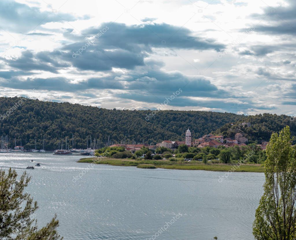 Town of Skradin seen from a nearby uphill road. River Krka flowing around the small town, belltower rising above the hill