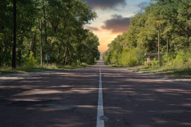 Terk edilmiş Çernobil Yasaklama Bölgesi 'nden geçen uzun düz bir yol. Sonsuz yol altın bir öğleden sonraya doğru gidiyor. Güzel bir gün batımı.