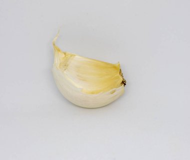 Beyaz arka planda kabuklu, soyulmamış bir sarımsak parçası izole edilmiş.