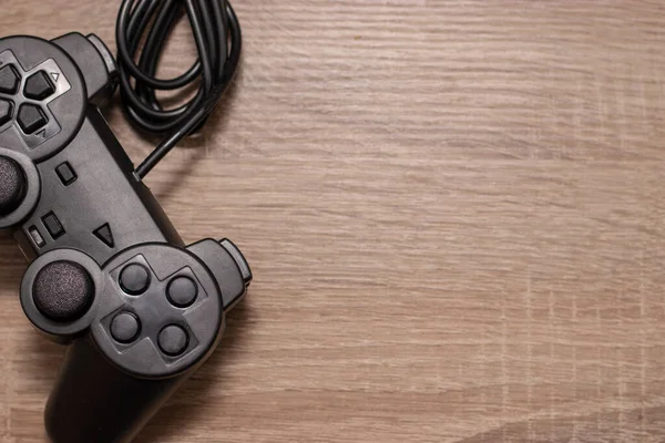 Console video gaming controller on wooden grey brown background. Cable rolled up in a ball , concept of gaming