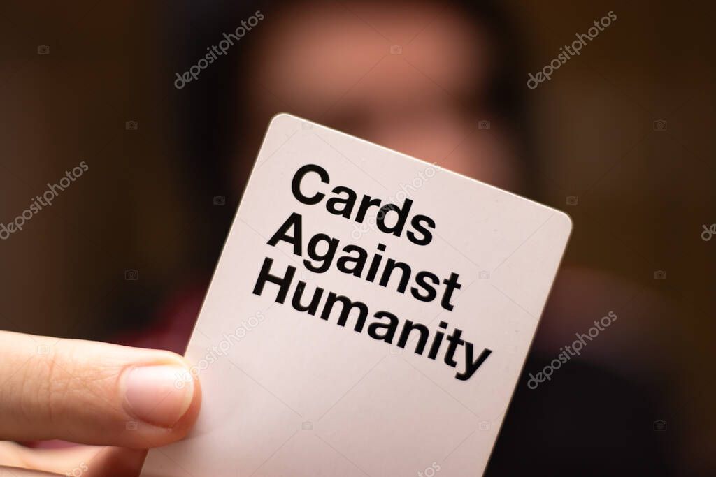 Split,Croatia April 2020 Dark blurred out of focus man in the background holding a white cards against humanity card, card filling the screen. Adult party game popular worldwide famous