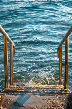 Çelik, güzel mavi denize açılan gümüş merdivenleri yansıtıyor. Hırvatistan 'da Adriyatik Denizi' nin açık deniz plajı