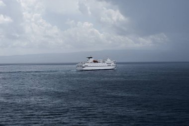 Split 'ten adalara giden büyük beyaz Hırvat feribotu. Yağmurlu bir fırtınada, denizde yapayalnız. Kara bulutlar uzanıyor.