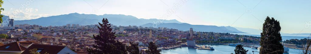 Very wide panorama of town of Split, Croatia seen from the Marjan hill. Early morning sunrise on a cold day, distant mountains blurred in the fog. Whole port and old houses visible