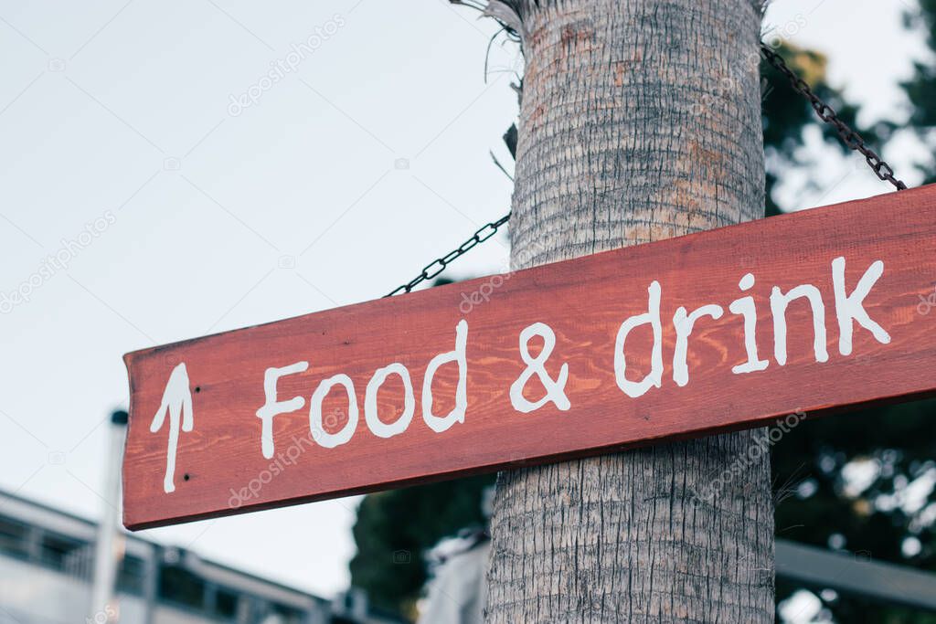 Food and drink sign on a tree pointing straight ahead