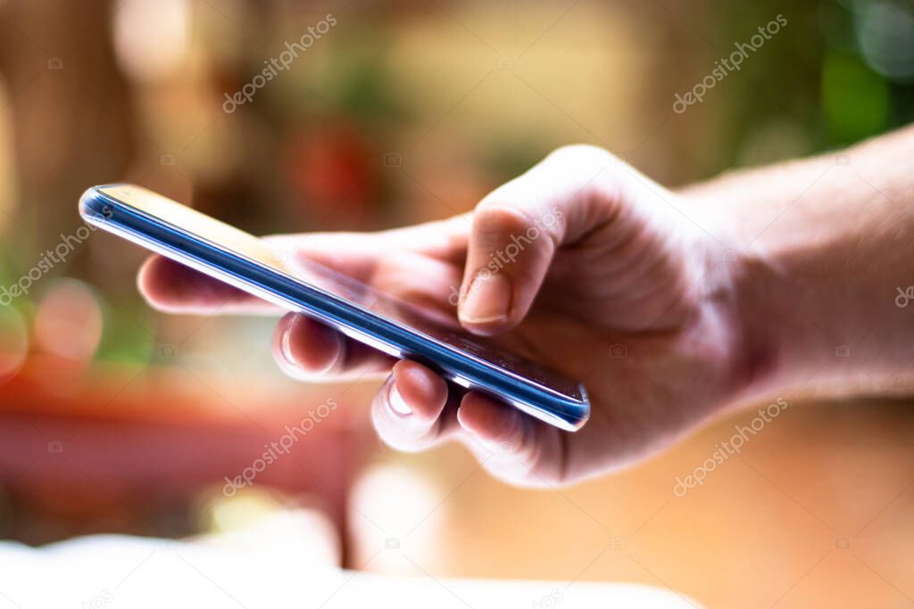 Hand holding a touch screen blue smartphone , phone tablet cellphone. Bokeh background blurred