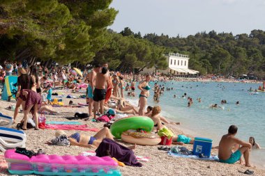 Hırvatistan 'da yaz sezonu başladı. Makarska 'daki popüler halk plajı. Her zamanki gibi aşırı kalabalık plaj salgını zamanında bile, insanlara dikkatli olmaları ve gruplardan uzak durmaları tavsiye ediliyor.