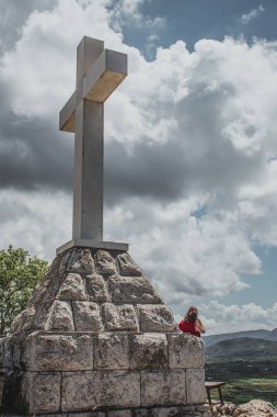 Hırvatistan 'ın Hvar adası Stargrad yakınlarındaki tepede dev beyaz modern haç. Altında duran kişi