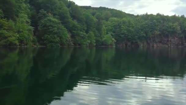 Panoramique au ralenti sur un immense lac dans le parc national croate des lacs de Plitvice. Reflet forestier de la surface de l'eau, fin de journée avec soleil doux