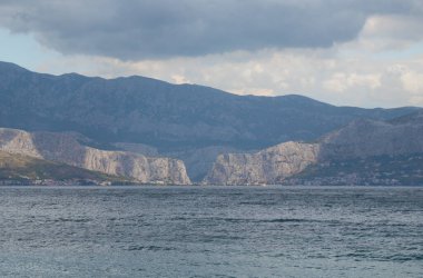 Hırvatistan 'ın Omis kentinin manzarası, Brac adasından çok uzaklardan görülüyor. Nehrin Adriyatik Denizi 'ne aktığı noktada iki dağ buluşuyor.