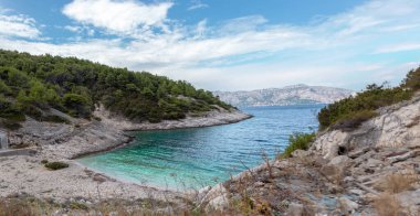 Hırvatistan 'ın Brac adasındaki gizli körfez plajı. Küçük cenneti çevreleyen orman ağaçlarıyla kayalık bir sahil. Yugoslav lider Tito 'ya ait gizli sığınağın önünde.