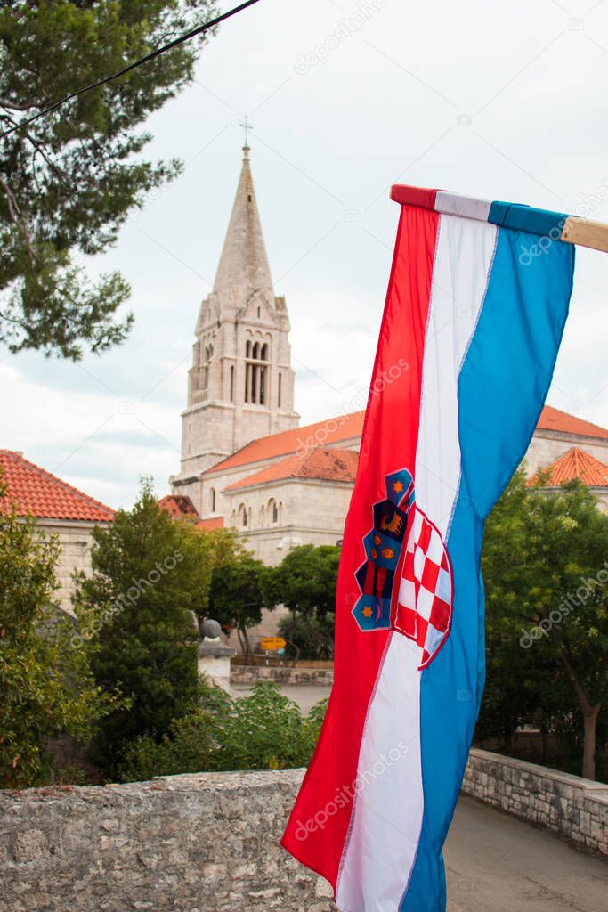 Closeup of the Croatian flag waving in the wind with the church in the village of Selca, Croatia in the background. Celebrating Croatian victory in the war of independence