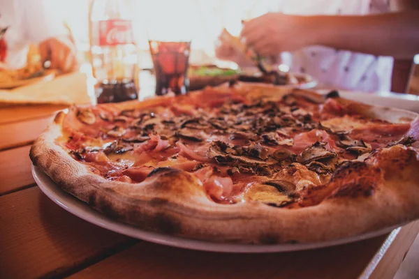 Akdeniz kıyısındaki bir restoranda servis edilen güzel bir mantarlı jambonlu peynirli pizzanın yakın çekimi.