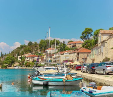 Brac Adası 'ndaki Bobovisca' nın küçük bir köyünün rıhtım manzarası. Kristal berrak deniz mavisi ve yeşil su parlak gökyüzünü yansıtır. Limana küçük tekneler yanaştı.