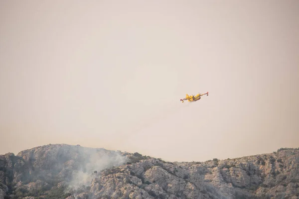 クロアチアのコザジャク山の頂上にある森林火災で水を落とす消防士 夏の山火事は地中海の乾燥した暖かい地域で非常に一般的です — ストック写真