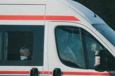 Bölünmüş Hırvatistan Eylül 2020 Beyaz Ambulans aracı yanından geçerken görüldü. Ön tarafta yüz maskesi takan üç sağlık görevlisi var. Yaşlı bayan arkada oturup pencereden bakıyor.