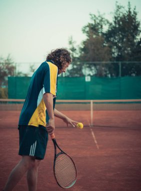 Hırvatistan 'ı Eylül 2020' de ikiye böl. Elinde raket ve top tutan bir adamın turuncu bir kil tarlasında tenis oynarken servis yapmaya hazırlandığını düşün.