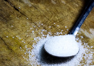 Tahta zemine karşı bir kaşık granüllü şeker.