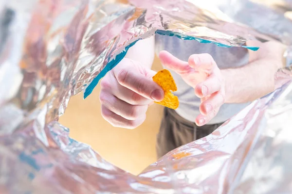 Poşetin manzarası, bir adamın eli çantanın içine uzanıp cips alacak bir şey arıyor. Abur cubur