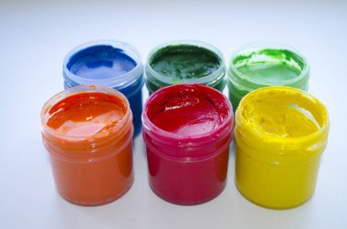 Açık arkaplanda plastik kavanozlarda çok renkli boyalar.