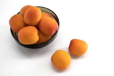 Güzel ve taze kayısılar beyaz arka planda bir fincanda.