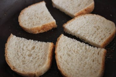 Metal bir tavada kızarmış beyaz ekmek dilimleri.