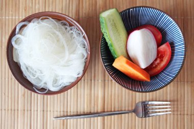 Sebzeli haşlanmış beyaz erişte ve tabakta çatal.