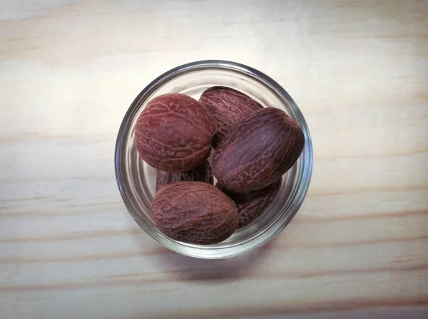 Dried Fragrant Nutmeg Seeds Glass Bowl Wooden Surface — Stock Photo, Image