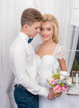 Gri bir stüdyoda el ele tutuşan güzel yeni evliler. Dantel bir elbise içinde gelin ve damadın portresi. Nazik bir düğün portresi..