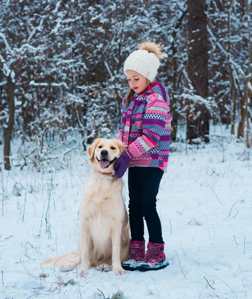 Smiling woman hugging her pet dog golden retriever near face. Golden retriever playing with a girl walking outdoors winter day, warm clothing. love and care for the pet.