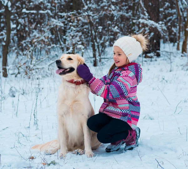 Smiling woman hugging her pet dog golden retriever near face. Golden retriever playing with a girl walking outdoors winter day, warm clothing. love and care for the pet.