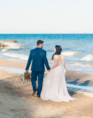 Güzel evli çift sahilde denize sıfır gün düğününde. Gelin ve damat gülümseyerek. Aşık genç bir çift. Arkadan görünüm