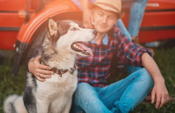Young man hugging husky dog in summer outdoors