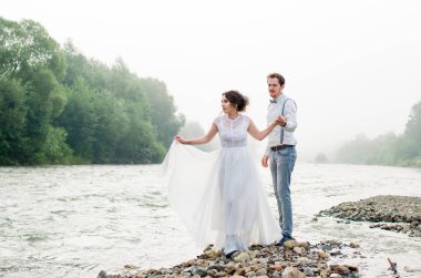 Güzel gelin ve damat. Sadece evlenmiş. Düğün çifti. Yakın çekim. Mutlu gelin ve damat onların düğün sarılma üzerinde. Gelin ve damat Dağları, güzel doğa, manzara, sis, akış