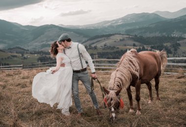 Düğün Gelin ve damadın dağlar kaya. dağın üzerinde çift öpüşme. Gelin ve Damat Düğün giysileri Dağları arka plan üzerinde bir atı ile.