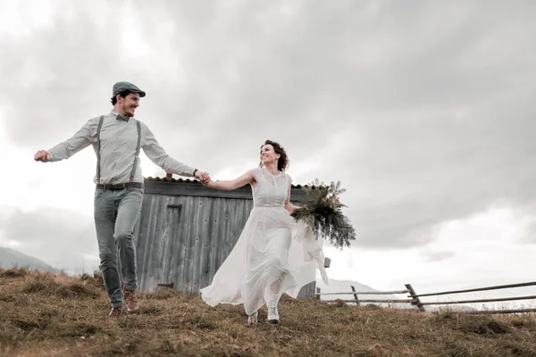 アメリカン スタイルの結婚式 山の夕暮れ時のフィールドのカップルを実行しています モダンなカップルは 式のためのアイデア 山の素晴らしい景色と美しいカップル — ストック写真