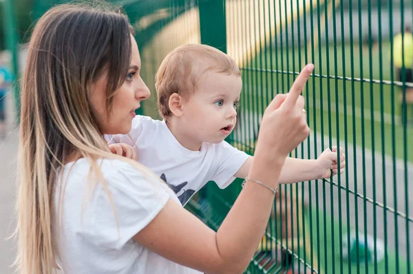 Glückliche Mutter hält süß lächelnden Sohn im Park — Stockfoto