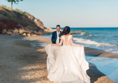 Düğün çifti, gelin ve damat deniz kenarında gelinlik giymişler.