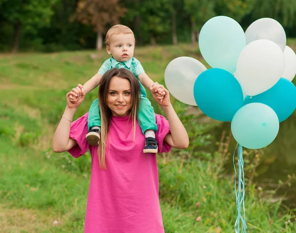 Junge und Mutter in der herbstlichen Natur mit buntem Luftballon. — Stockfoto