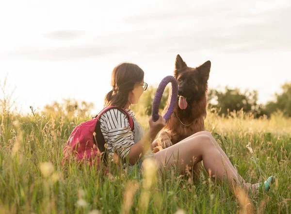Ung kvinna leker med sin tyska herde hund i parken — Stockfoto