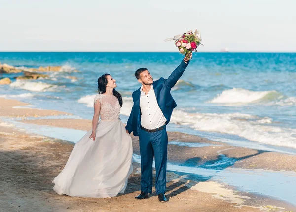 Pareja de boda, novio y novia en vestido de novia cerca del mar en la playa — Foto de Stock