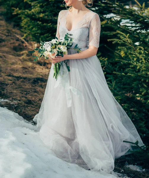 Bella sposa bruna in chiffon abito da sposa leggero ricamato con perline in posa vicino alle montagne — Foto Stock