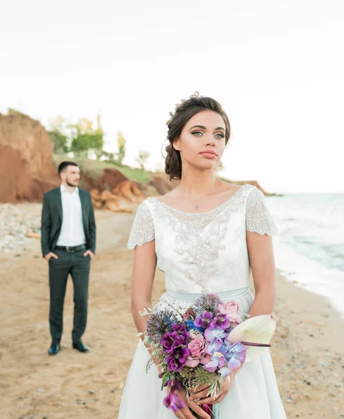 Casamento casal, noivo e noiva em vestido de noiva perto do mar à beira-mar — Fotografia de Stock