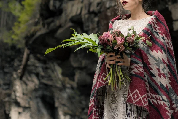 Beautiful brunette bride in light chiffon wedding dress embroidered with beads posing near the mountains — Stock Photo, Image