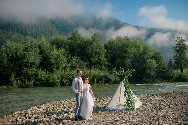完璧なビューで山の近くに立っている美しいの結婚式のカップル — ストック写真