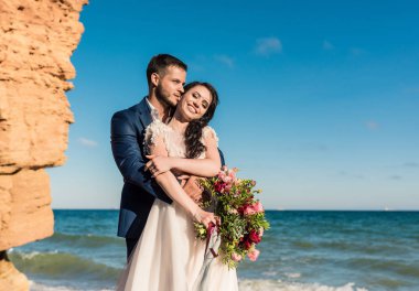 Düğün çifti, gelin ve damat deniz kenarında gelinlik giymişler.