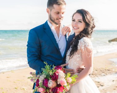 Düğün çifti, gelin ve damat deniz kenarında gelinlik giymişler.