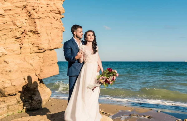 Весільна пара, наречена і наречена у весільній сукні біля моря на узбережжі — стокове фото
