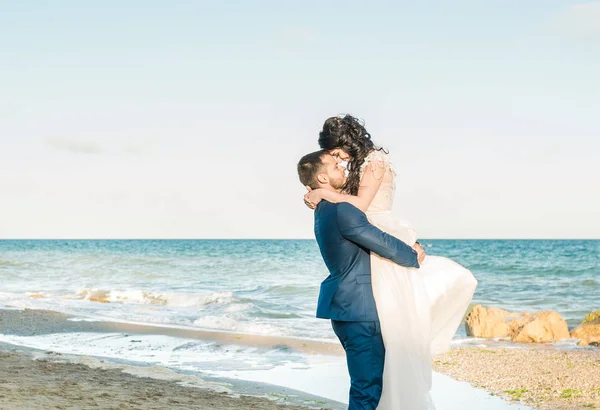 Весільна пара, наречена і наречена у весільній сукні біля моря на узбережжі — стокове фото
